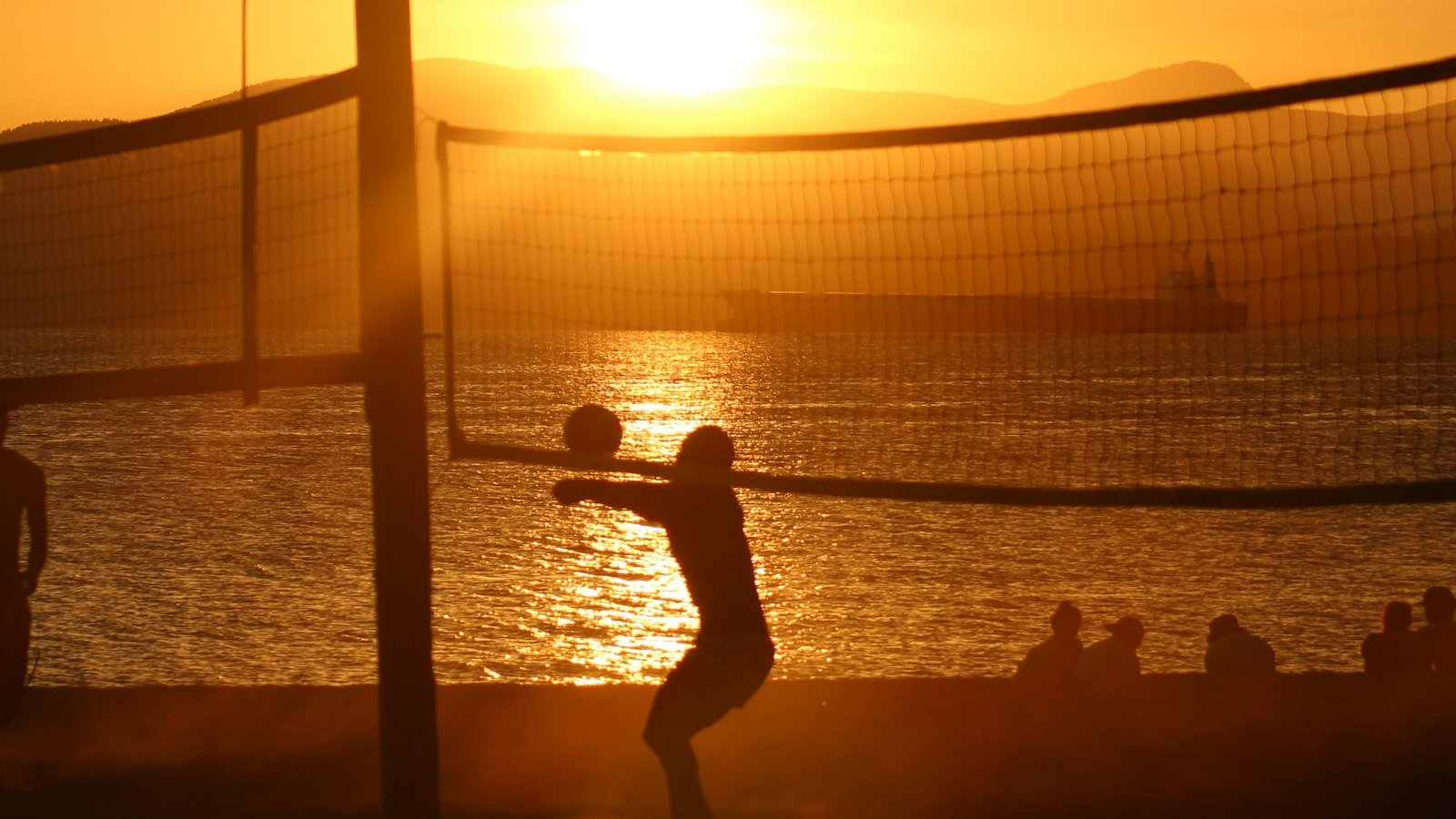 Jogador junto à rede de praia ao pôr do sol