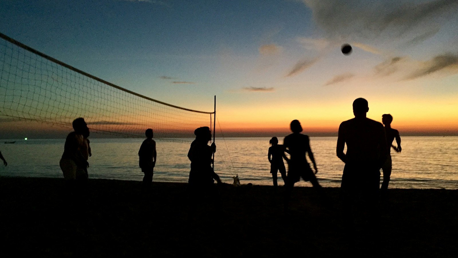 Grupo jogando na praia ao pôr do sol