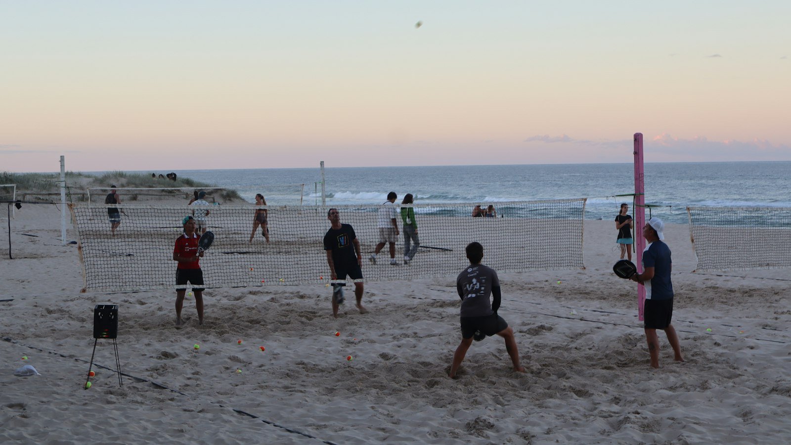 Partida de beach tênis na praia ao entardecer